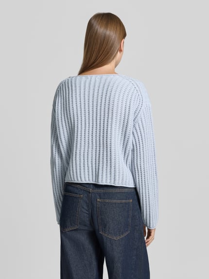 Vrouwenmodel draagt gebreide pullover met ronde hals Model 'IMENY' van DRYKORN, materiaalmix met alpaca, regular fit, ruglengte maat S 47 cm, mouwlengte maat S 58 cm, lichtblauw met ribstructuur, detailrijke textuur, denim broek, volledig zicht van achteren.