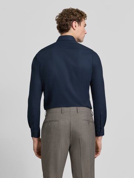 Männermodel trägt Slim Fit Businesshemd mit Kentkragen von OLYMP in Dunkelblau mit feinem Web muster, Longline, Rückenansicht, Ganzkörperansicht.