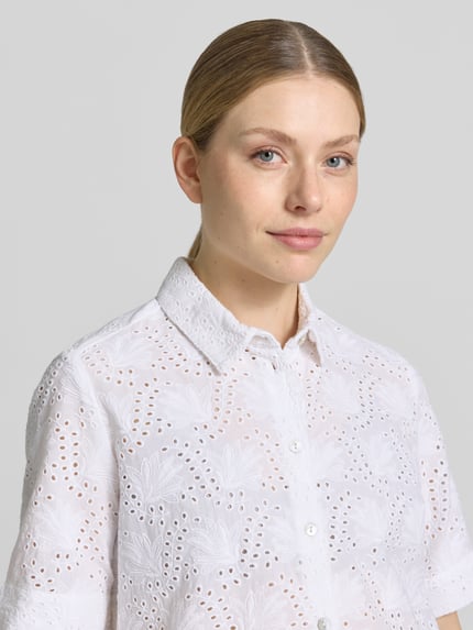 Frauenmodel trägt Bluse mit Lochstickerei und Hemdblusenkragen von Christian Berg Woman aus Reine Baumwolle, Nahaufnahme Oberkörper.