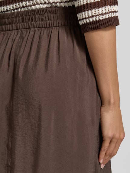 Kobiece model prezentuje spódnica midi z mieszanki modalu, linia a, model 'Ronella' od OPUS, elastyczny pas, detal bokiem, zbliżenie na górną część spódnicy.