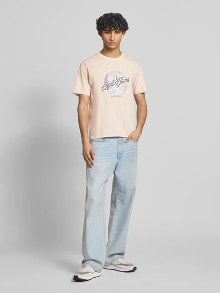 Męski model nosi T-Shirt mit Rundhalsausschnitt Modell 'HONOLULU' von Jack & Jones z bawełny, krój regular fit, nadruk, okrągły dekolt, długość tyłu w rozmiarze M: 68 cm, jasnoróżowy, prosty fason, gładka tekstura, Ganzkörperansicht von vorne