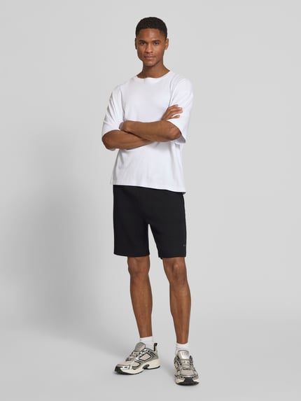 Männermodel trägt Regular Fit Sweatshorts aus Baumwoll-Mix Modell 'JT_GLOBE' von BOSS Green, schwarz, unifarben, Ganzkörperansicht von vorne.