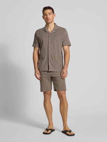 Männermodel trägt Regular Fit Shorts mit Label-Patch von Lindbergh im Baumwoll-Mix mit Eingrifftaschen, Ganzkörperansicht von vorne.