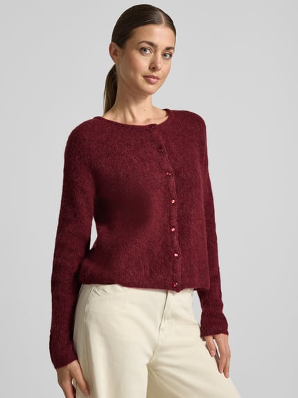 Frauenmodel trägt Strickjacke aus Alpaka-Mix von MOS MOSH in Dunkelrot mit geripptem Rundhalsausschnitt und Knopfleiste, lockere Passform, Ganzkörperansicht von vorne.