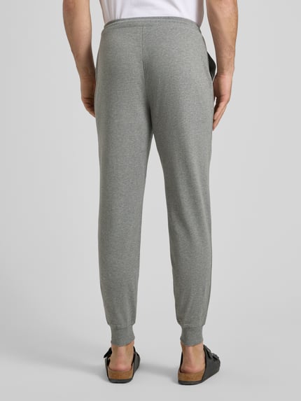 Mężczyzna nosi Sweatpants mit elastischem Bund und Tunnelzug von JOOP! Collection, bawełniany miks ze stretchem, krój regular fit, widok całej sylwetki od tyłu.