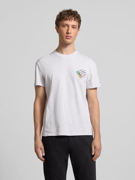 Männermodel trägt Regular Fit T-Shirt aus reiner Baumwolle von Tommy Jeans in Weiß mit Label Print, Rundhals, gerade Kurzarm, Ganzkörperansicht von vorne.