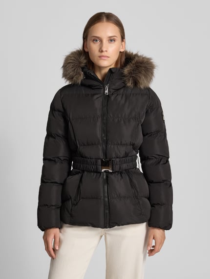 Frauenmodel trägt Mantel in Stepp-Optik Modell 'FUJI' von Superdry mit Kunstfellbesatz und Gürtel, schwarze Farbe, Ganzkörperansicht von vorne.