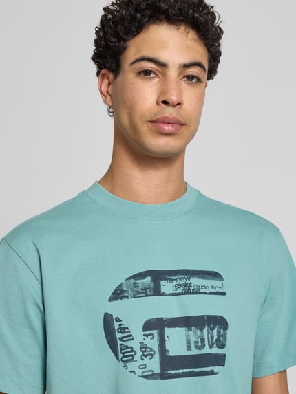Männermodel trägt Regular Fit T-Shirt mit Logo-Print Modell 'icon' von G-Star Raw in Hellblau, reine Baumwolle, Nahaufnahme Oberkörper.