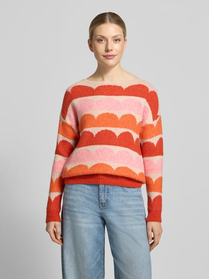 Frauenmodel trägt Relaxed Fit Strickpullover aus elastischem Woll-Mix von ZABAIONE, mehrfarbig mit Muster, U-Boot-Ausschnitt, Ganzkörperansicht von vorne. Damen Strickpullover, Rückenlänge 55 cm, Ärmellänge 53 cm, Modell 'Ha44rlow'.