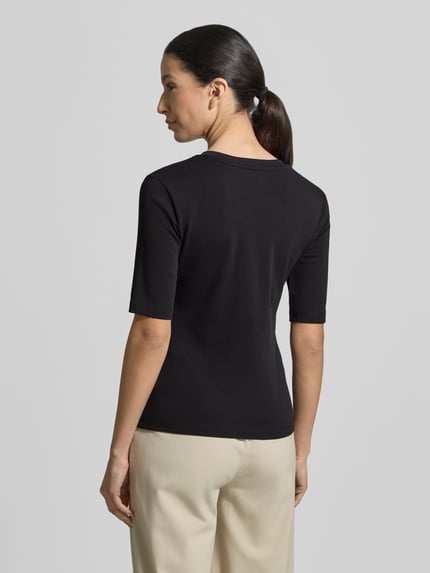 Vrouwenmodel draagt T-shirt met V-hals van Christian Berg Woman, zwart, mix van katoen en elastaan, regular fit, 1/2-mouwen, ruglengte maat S 55 cm. Ganzkörperansicht Rückansicht.