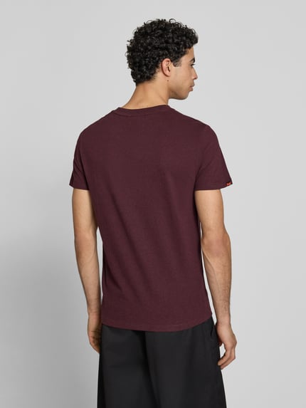 Männermodel trägt Regular Fit T-Shirt mit Logo-Stitching von Superdry in Dunkelrot aus Reine Baumwolle, Rückenlänge 69 cm, Ganzkörperansicht Rückansicht.