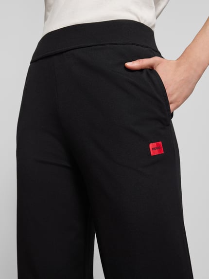 Frauenmodel trägt Comfort Fit Sweatpants aus Baumwoll-Modal-Mix Modell 'SIGNATURE' von HUGO, Optik: Unifarben, Label-Stitching-Applikation, Bundabschluss und Beinabschluss elastisch, seitliche Eingrifftaschen, Material Baumwoll-Modal-Mix, Nahaufnahme Oberkörper.