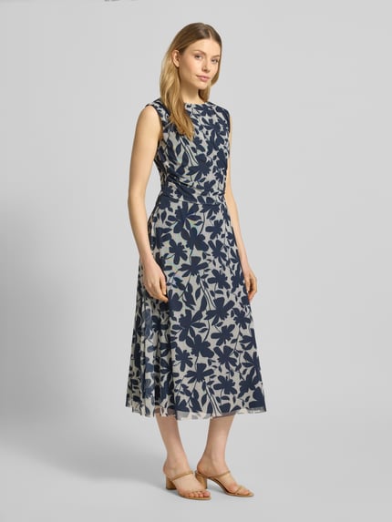 Frauenmodel trägt Regular Fit Midikleid mit floralem Allover-Print von Swing in Blau mit Rundhalsausschnitt, Ärmelloses-Design, Elastischer-Material-Mix, Nahtreißverschluss, Raffungen, Taillierte Passform, blickdichtem Unterrock, Ganzkörperansicht von vorne.