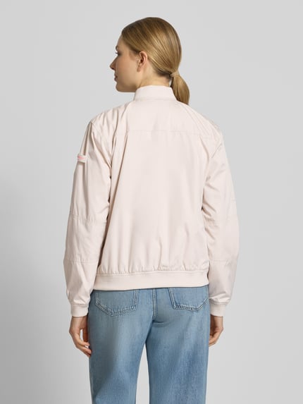 Frauenmodel trägt Regular Fit Bomberjacke mit Stehkragen Modell 'Brooklyn' von Frieda & Freddies in Hellrosa, glatte Textur, elastische Abschlüsse, Eingrifftaschen und Reißverschluss, kombiniert mit blauen Jeans, Rückansicht, Ganzkörperansicht. Rückenlänge bei Größe 36: 59 cm, Schulterbreite: 44 cm, Brustweite: 52 cm, Ärmellänge: 51 cm.