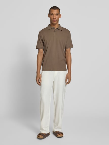 Männermodel trägt Regular Fit Poloshirt reiner Baumwolle Modell 'COLE' von SELECTED HOMME in Braun, strukturierte Optik, Ganzkörperansicht von vorne.