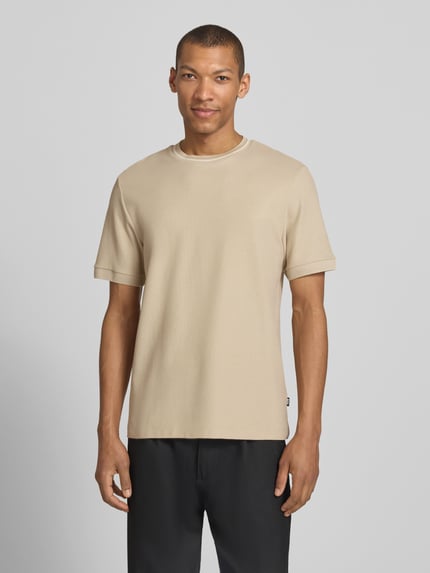Männermodel trägt Regular Fit T-Shirt aus reiner Baumwolle Modell 'C-TAUT-40' von BOSS in Beige, Struktur Piqué, Ganzkörperansicht von vorne.