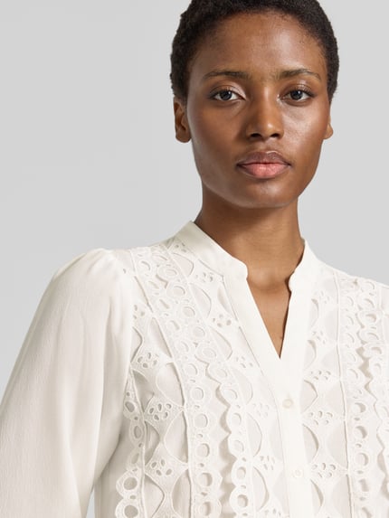 Frauenmodel trägt Bluse mit Viskose-Anteil von MORE & MORE in Creme, Spitzendetails, strukturierte Oberfläche, Nahaufnahme Oberkörper, taillierte Passform, Knopfleiste, Material-Mix.