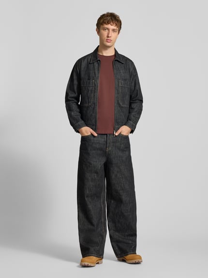 Männermodel trägt Jeansjacke mit Zweiwege Reißverschluss von ONLY in dunkler Rinse Washed Denim-Optik, Strukturmuster, Ganzkörperansicht von vorne.