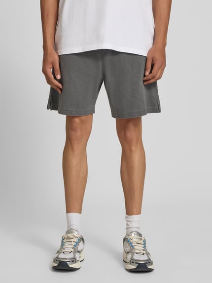 Männermodel trägt Regular Fit Shorts mit elastischem Bund Modell 'Harper' von Carhartt Work In Progress aus Reine gewachste Baumwolle, Grauton, glatte Textur, Herren Shorts, Ganzkörperansicht von vorne.
