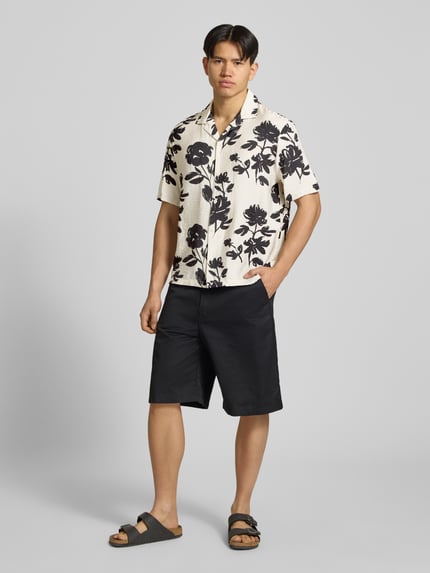 Männermodel trägt Regular Fit Freizeithemd aus Viskose-Mix von REVIEW mit Reverskragen, 1/2-Arm, Knopfleiste, Schwarz-Weiß-Print, Ganzkörperansicht von vorne.