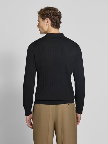 Männermodel trägt czarną koszulkę polo z pionowym prążkowaniem, beżowe spodnie, Regular Fit Poloshirt aus reiner Baumwolle Modell 'TORINO' von Selected, Herren Poloshirt, Ganzkörperansicht Rückansicht