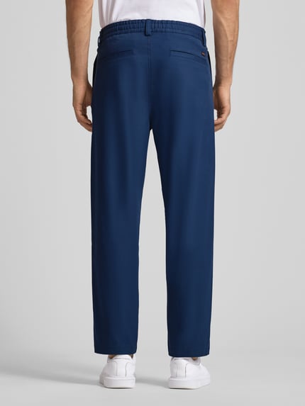 Männermodel trägt Tapered Chino mit Kordelzug Modell 'CHINO ST-P' von BOSS Orange, Optik: Unifarben, Baumwoll-Mix, Ganzkörperansicht Rückansicht.