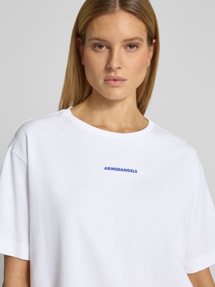 Vrouwenmodel draagt oversized t-shirt uit puur katoen model 'GIANNAA CHAANGE' van Armedangels in effen kleuren met labelprint, ronde hals, korte mouw, fijnrib structuur, nahaufnahme bovenlichaam.