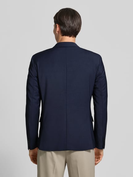 Męski model nosi marynarkę na 2 guziki w jednokolorowy design z mieszanka bawełny i dodatkiem streczu od CK Calvin Klein, krój regular fit, kieszenie z patką, długość tyłu w rozmiarze 50: 73 cm, szerokość w rozmiarze 50: 47 cm, długość rękawów w rozmiarze 50: 65 cm, widok całej sylwetki od tyłu.