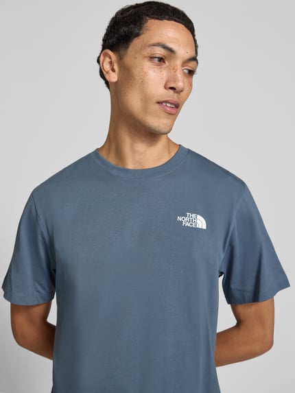 Männermodel trägt T-Shirt mit Label-Print Modell 'Evolution' von The North Face in Blau, Baumwoll-Mix, Regular Fit, Nahaufnahme Oberkörper.