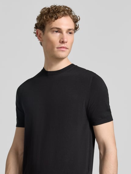 Männermodel trägt Strickshirt mit Rundhalsausschnitt von MARKUP, Regular Fit in Schwarz, feine Struktur, Nahaufnahme Oberkörper.