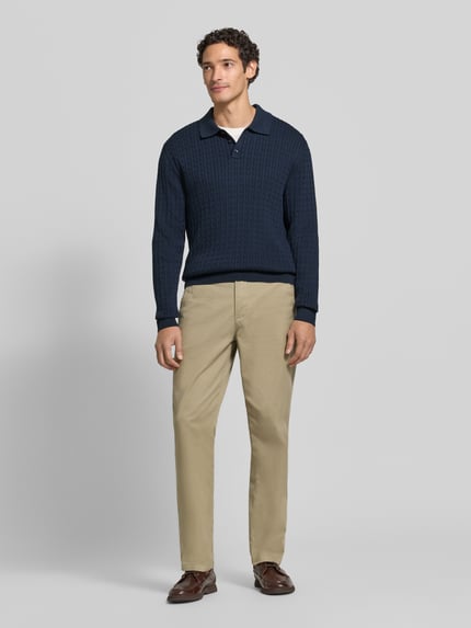 Męski model nosi Strickpullover mit Polokragen und kurzer Knopfleiste von MCNEAL, bawełna, krój regular fit, ścieg warkoczowy, kołnierzyk polo, prążkowane wykończenia, długość tyłu w rozmiarze M: 71 cm, długość rękawów w rozmiarze M: 78 cm, widok całej sylwetki z przodu.