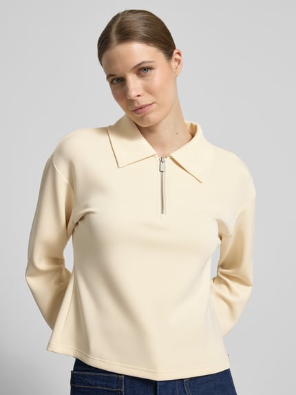 Frauenmodel trägt Sweatshirt mit Reißverschluss von Scotch & Soda in Beige, Material-Mix mit Lyocell-Anteil, Regular-Fit, Umlegekragen, Nahaufnahme Oberkörper.