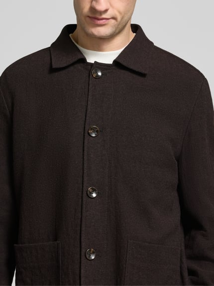 Männermodel trägt Blouson Modell 'Dellin' von STRELLSON in Dunkelbraun mit Umlegekragen und Pattentaschen, Nahaufnahme Oberkörper.