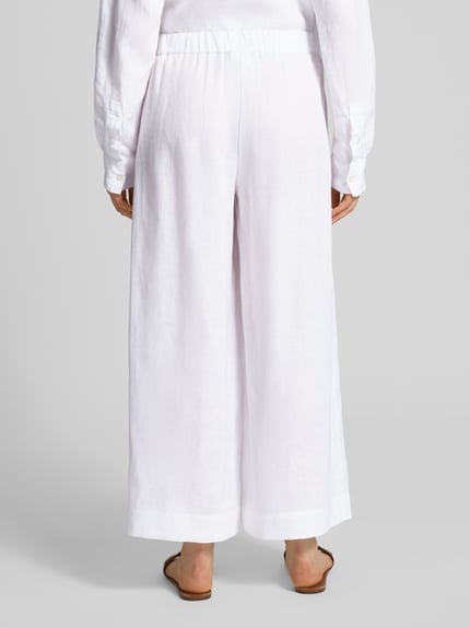 Frauenmodel trägt Culotte aus Leinen mit elastischem Bund Modell 'CANNETI' von MM by Max Mara in Weiß, Wide Leg Fit, reine Leinenstruktur, französische Eingrifftaschen, Ganzkörperansicht Rückansicht.