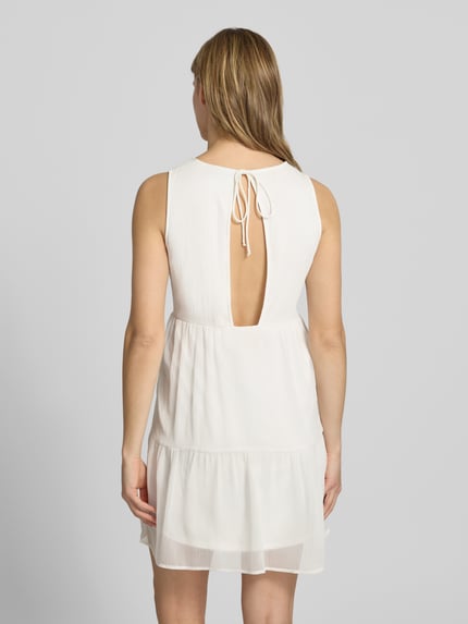 Frauenmodel trägt Regular Fit Chiffonkleid in Crêpe-Optik Modell 'LARA' von Pieces, unifarben, Mini-Länge, Rückenausschnitt mit Bindeband, Ganzkörperansicht Rückansicht.