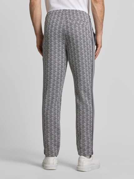 Männermodel trägt Regular Fit Sweathose mit Baumwoll-Anteil von Lacoste, grau gemustert mit grafischem Muster, Ganzkörperansicht Rückansicht. Herren Sweathose von Lacoste