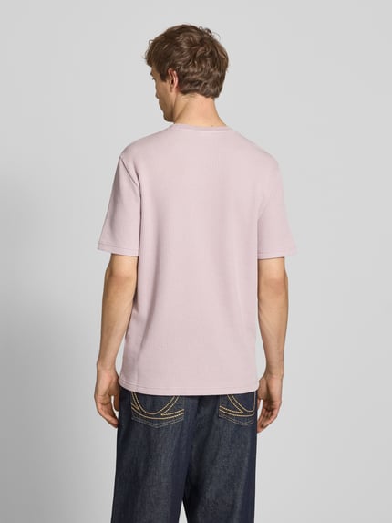 Männermodel trägt T-Shirt mit Strukturmuster und Label-Stitchings von CHAMPION in hellem Pastell, Baumwoll-Mix, Regular Fit, Ganzkörperansicht Rückansicht.