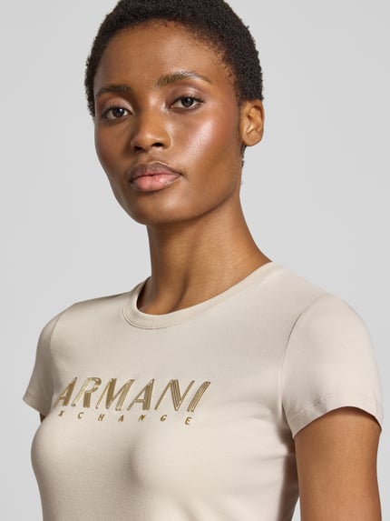 Frauenmodel trägt Slim Fit T-Shirt mit Label-Print von Armani Exchange, beige, Rundhalsausschnitt, Baumwoll-Elasthan-Mix, Nahaufnahme Oberkörper.