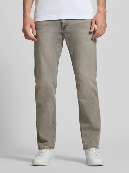 Mężczyzna nosi Regular Fit Jeans im Used-Look Modell 'CLARK' von JACK & JONES, mieszanka bawełny z dodatkiem streczu, wpuszczane kieszenie, szerokość w rozmiarze 32/32: 42 cm, długość wewnętrzna nogawki 75 cm, efekt znoszenia, jasnoszary, krój regular fit, zdjęcie całej sylwetki od przodu.