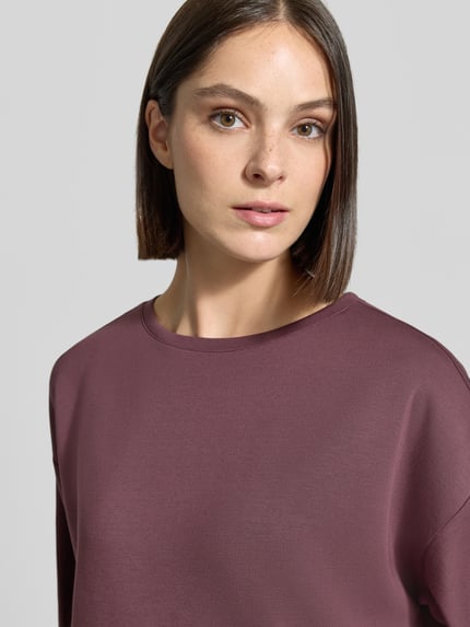 Frauenmodel trägt Oversized Fit T-Shirt aus elastischem Material-Mix von Christian Berg Woman, mattes Violett, glatte Textur, Nahaufnahme Oberkörper.