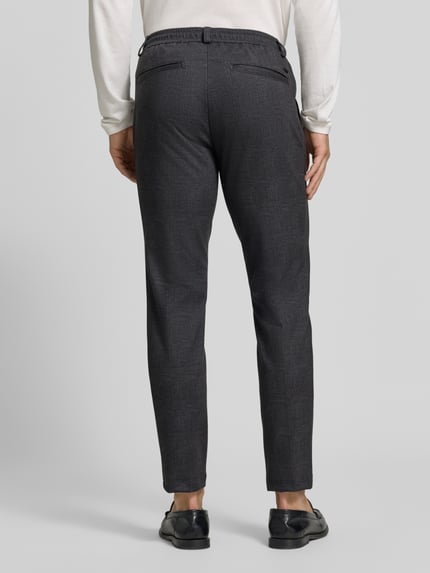 Männermodel trägt dunkelgraue, weite Hose Tapered Fit Jogpants aus reiner Baumwolle Modell 'Phil' von Brax, Herrenmode, Ganzkörperansicht Rückansicht.