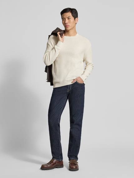 Männermodel trägt Slim Fit Pullover in Strick-Optik von ARMANI EXCHANGE, cremeweiß, reine Baumwolle, Rundhalsausschnitt, Ganzkörperansicht von vorne