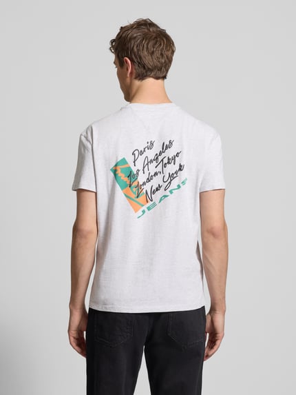 Männermodel trägt Regular Fit T-Shirt aus reiner Baumwolle von Tommy Jeans, unifarben mit Label Print, Jersey-Textur, Ganzkörperansicht Rückansicht.