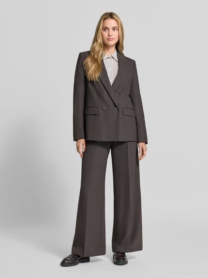 Frauenmodel trägt Oversized Blazer mit Reverskragen von COMMA in Dunkelbraun, doppelte Knopfleiste, Pattentaschen, Ganzkörperansicht von vorne. Rückenlänge 69 cm, Brustweite 51 cm, Ärmellänge 63 cm, Oversized Fit.