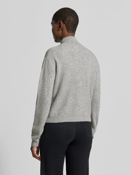 Frauenmodel trägt Relaxed Fit Strickjacke aus reiner Wolle Modell 'Tracy' von My Essential Wardrobe in Grau mit geripptem Stehkragen, Ganzkörperansicht Rückansicht.