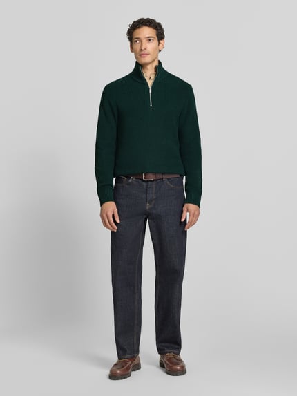 Männermodel trägt Slim Fit Strickpullover aus reiner Baumwolle mit Troyer-Kragen von MCNEAL in Dunkelgrün, lange Ärmel, gerippte Abschlüsse, Ganzkörperansicht von vorne.