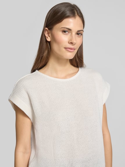 Modelka kobieca nosi Relaxed Fit T-Shirt in Strick-Optik Modell 'Sofrano' od OPUS, biały bawełniany melanż, krótki rękaw, okrągły dekolt, elastyczny dół, długość pleców w rozmiarze 36: 56 cm, ujęcie z przodu na górną część ciała.