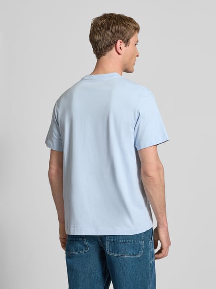 Männermodel trägt T-Shirt mit Label-Print und Rundhalsausschnitt von Calvin Klein Jeans in Hellblau, reine Baumwolle, Regular-Fit, Ganzkörperansicht Rückansicht.
