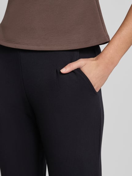 Frauenmodel trägt Sweatpants mit elastischem Bund von Christian Berg Woman, schwarzer Stoff, sichtbare Bundfalten, Regular Fit, Nahaufnahme Oberschenkel. Material-Mix mit Modal-Anteil.