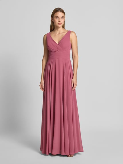 Frauenmodel trägt Maxikleid aus Chiffon in Wickel-Optik von TROYDEN COLLECTION in A-Linie, altrosa, fließende Textur, Ganzkörperansicht von vorne.